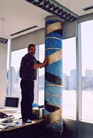 The artist installing the painting over the column in Dr Tom Hudson's office.