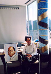 Dr Tom Hudson with his portrait and Neo-Rupestrian DNA Double Helix (gold) in his office.